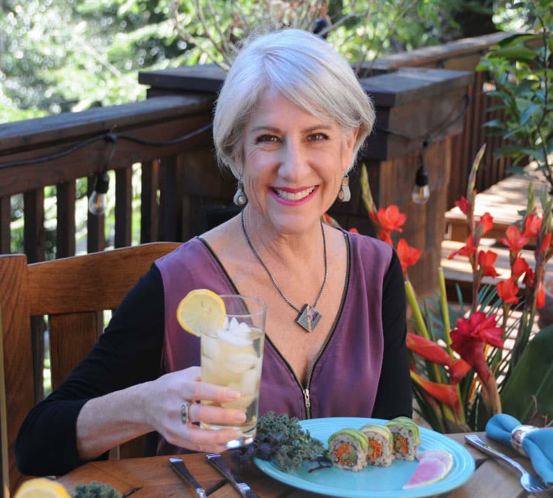 Darcie Ellyne sits at an outdoor table with a healthy meal and a glass of lemonade